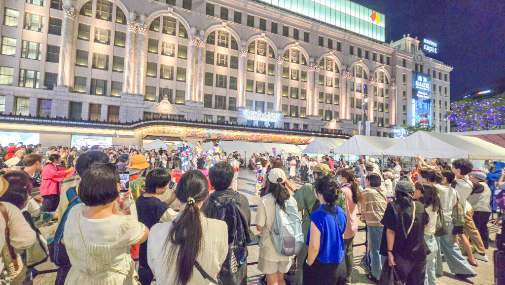 「大阪ミナミ夏祭り＆にぎわいスクエア2025」の盆踊りで踊る人たちを観覧する人たち