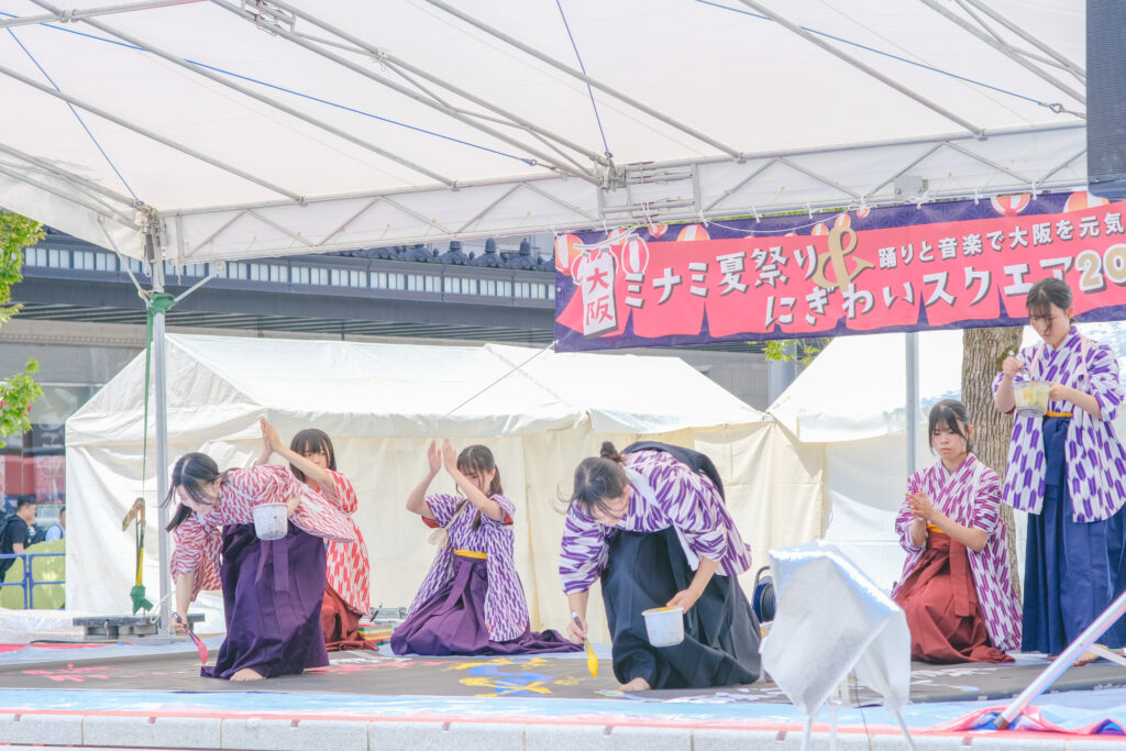 八尾高校書道部による、なんば広場で開催した大阪ミナミ夏祭り＆にぎわいスクエア2025のオープニングアクトの様子